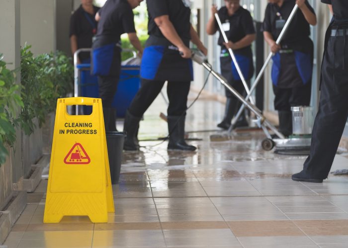 Cropped image of group of woman in protective gloves using a flat wet-mop and machine while cleaning floor